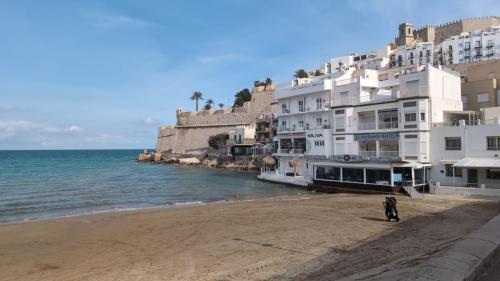 una persona che cammina su una spiaggia accanto a un edificio di Apartamento BenRif a Santa Magdalena de Pulpis