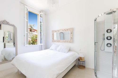 une chambre blanche avec un lit et un miroir dans l'établissement Palais Beaulieu Magnifique 3p 2 chambres, à Cannes