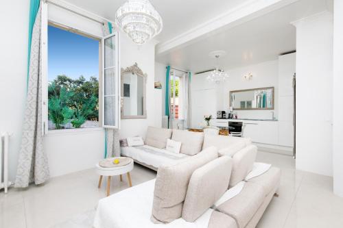un salon avec des meubles blancs et une grande fenêtre dans l'établissement Palais Beaulieu Magnifique 3p 2 chambres, à Cannes