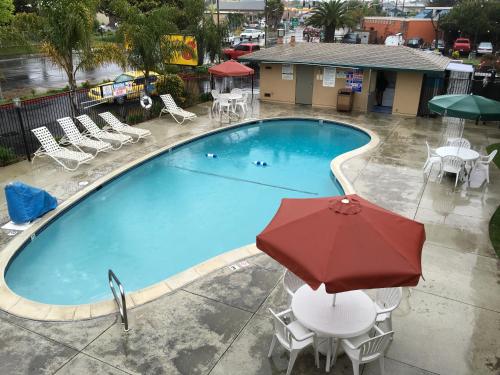 a swimming pool with a red umbrella and chairs and tables at Super 8 by Wyndham Salinas in Salinas