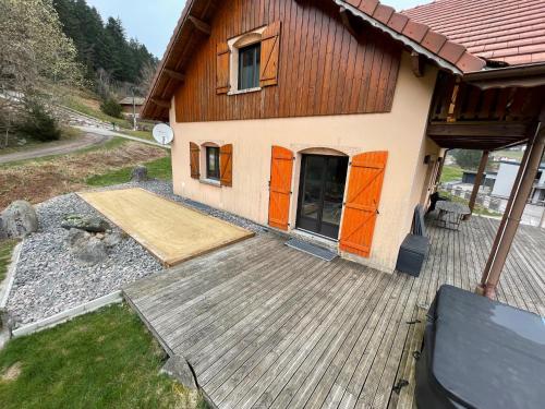 a house with orange doors on a wooden deck at La Gouleote Spacieuse maison type chalet avec jacuzzi, sauna, pétanque in Gérardmer