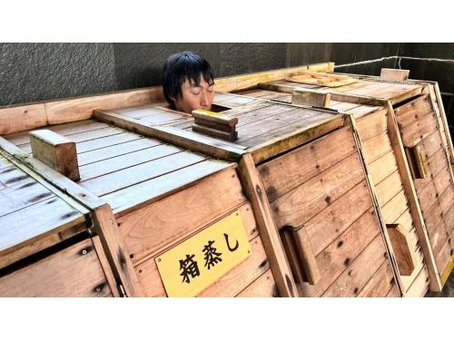 a man is sitting in a wooden box at Miki no Sato Hotel Miki - Vacation STAY 51868v in Gero