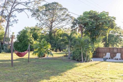 a hammock in a yard with two chairs and trees at Elegant Palm Bay Getaway with Large Backyard in Palm Bay