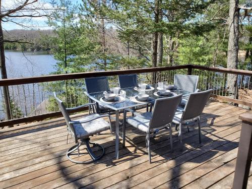 a table and chairs on a deck with a view of a lake at Boulder Lakehouse in Boulder Junction