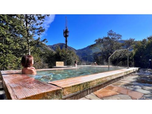 a woman sitting in a swimming pool with mountains in the background at Miki no Sato Hotel Miki - Vacation STAY 51868v in Gero