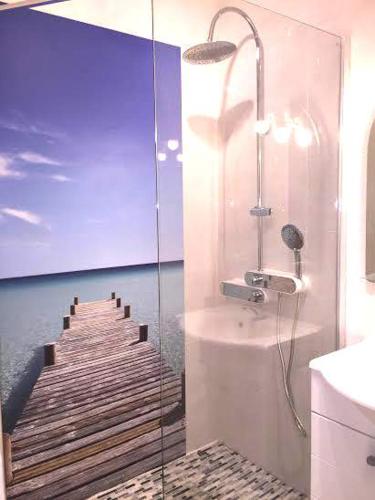 - une salle de bains pourvue d'une douche à l'italienne à côté d'une jetée en bois dans l'établissement Barcaresa-Magnifique Appartement residence Argonautes, au Barcarès