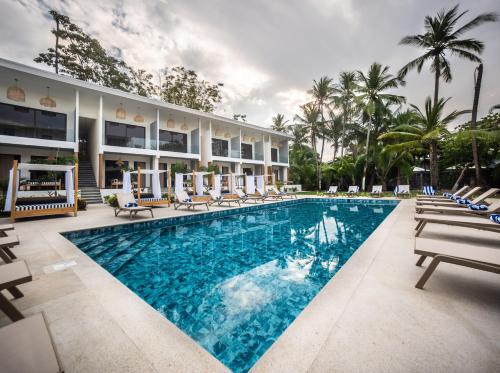 a pool at a resort with chairs and a building at Lia Hotel Jaco in Jacó