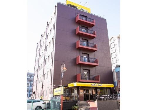a tall building with red balconies on a city street at Smile Hotel Kumamoto Suizenji - Vacation STAY 59277v in Kumamoto