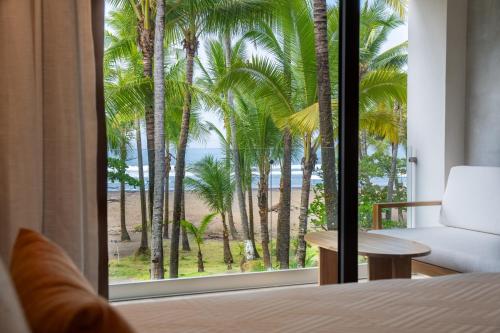 a bedroom with a view of the ocean and palm trees at Lia Hotel Jaco in Jacó