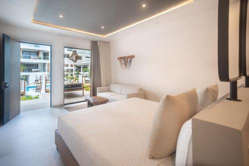 a hotel room with a white bed and a couch at Lia Hotel Jaco in Jacó