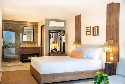a bedroom with a white bed and a bathroom at Lia Hotel Jaco in Jacó