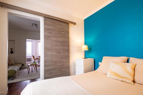 - une chambre avec un grand lit blanc et un mur bleu dans l'établissement Charming Apartment in heart of Paris, à Paris