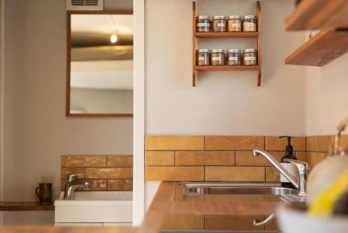 a kitchen counter with a sink and a mirror at The Secret Studio, Outdoor Bath & Pizza Oven in New Plymouth