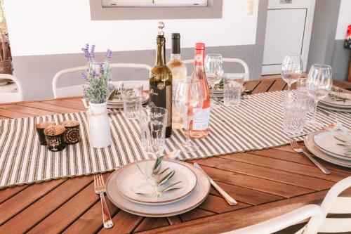 a wooden table with plates and wine bottles on it at Luxe villa for 8 - Heated Pool -AC -BBQ Area - Patio - 160Mbps - Olives - Palm - vineyard in Santa Luzia