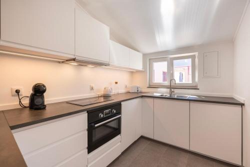 a kitchen with white cabinets and a sink and a stove at Estoril Haven in Cascais
