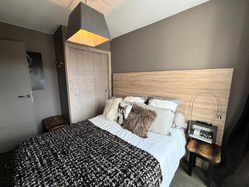 une chambre avec un grand lit avec une tête de lit en bois dans l'établissement Résidence Le Panoramic - Appartement chaleureux · Départ et retour skis aux pieds · Piscine · Spa MAE-6941, à Magland