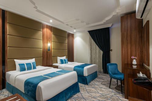a hotel room with two beds and a desk at Alqasr Altahaliyh in Khamis Mushayt