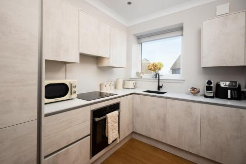 a kitchen with white cabinets and a microwave at Stylish Maisonette with View in Tweedmouth