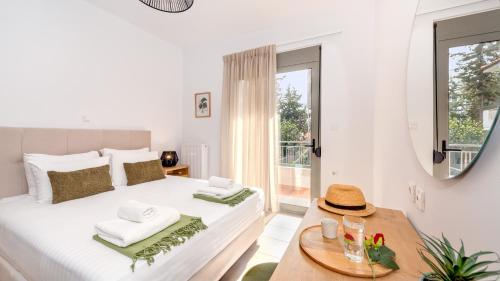 a white bedroom with a large bed and a mirror at Casa Kamara in Kounoupidhianá