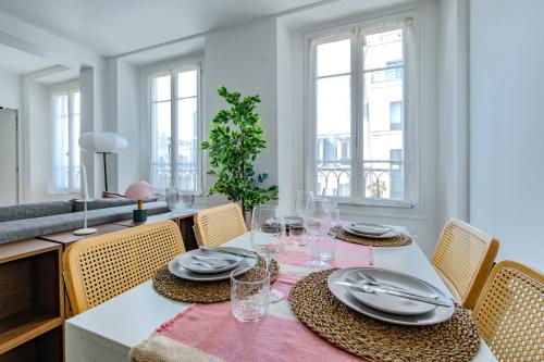 une salle à manger avec une table, des assiettes et des verres dans l'établissement Cosy Apt 6 Guests for Family, à Paris