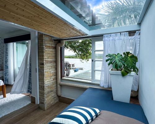 a bedroom with a window and a potted plant at Hotel Boutique Recanto da Passagem in Cabo Frio