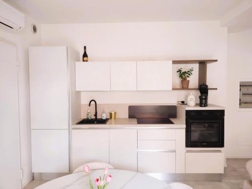 a white kitchen with a sink and a stove at L'incanto sui colli con giardino privato in Pianoro