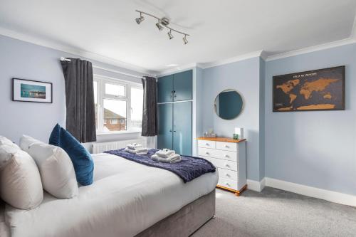 a bedroom with a bed with blue walls and a dresser at Melrose- Beautiful 4 Bedroom Home With Parking in Brighton & Hove