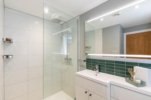 a bathroom with a shower and a sink and a mirror at Melrose- Beautiful 4 Bedroom Home With Parking in Brighton & Hove