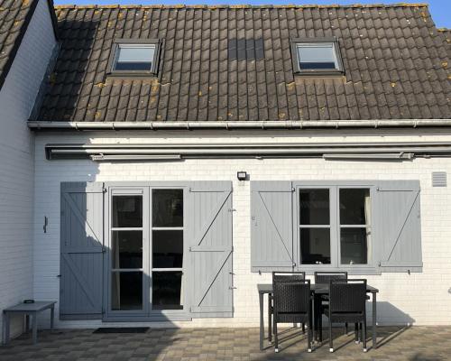 a table and chairs in front of a white building at Zeebos 112 in Bredene