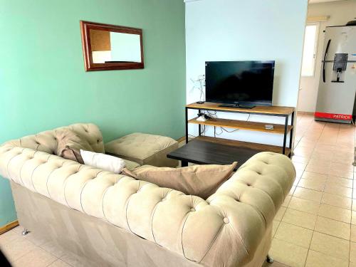 a living room with a couch and a television at Tu espacio ideal, Amplia y Luminosa en Rio gallegos in Río Gallegos