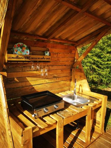 - une cuisine extérieure avec un évier dans une cabane en bois dans l'établissement La roulotte des nuits étoilées du moulin, à Sainte-Orse