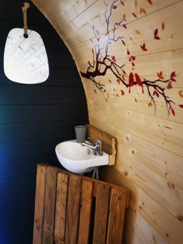 La salle de bains est pourvue d'un lavabo dans un mur en bois. dans l'établissement La roulotte des nuits étoilées du moulin, à Sainte-Orse
