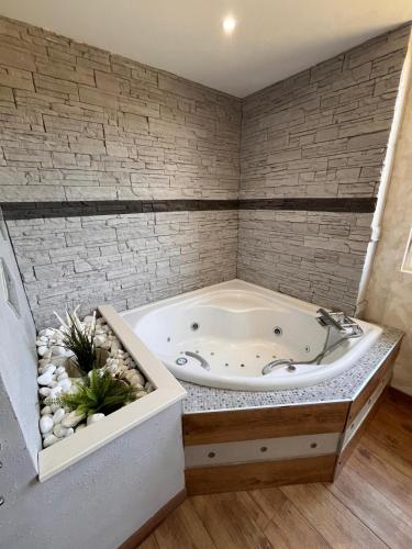 Cette chambre dispose d'une baignoire et d'un mur en briques. dans l'établissement Villa Mahloa, à Saint-Yaguen