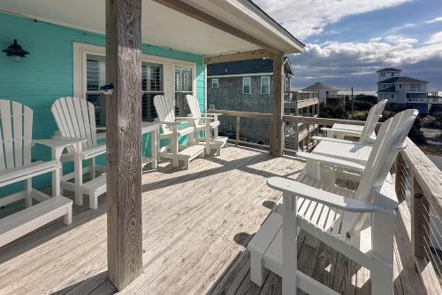 a porch with white chairs and tables on a blue house at Days to Remember in Avon