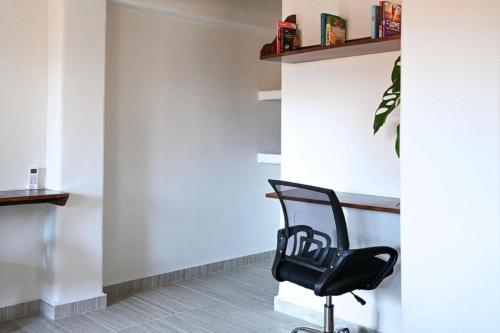 a black chair sitting in a room with a wall at Ixic posada boutique in Zihuatanejo