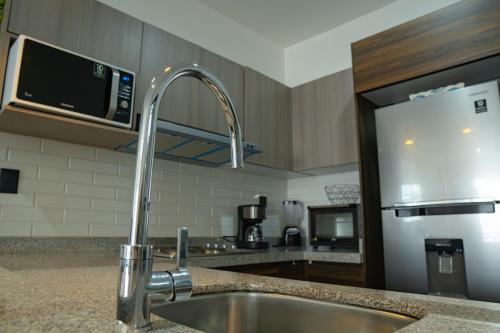 Una cocina con fregadero y frigorífico de acero inoxidable. en few steps from the beach, at golden zone, en Mazatlán