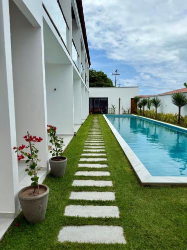 a backyard with a swimming pool and grass at Yahweh Hotel in São Miguel do Gostoso
