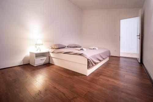 a white bedroom with a bed and a lamp on a wooden floor at Apartment Grguric Apartments in Palit