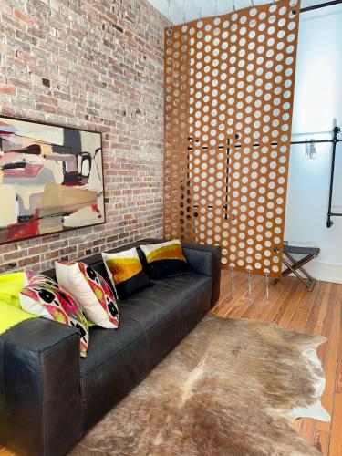 a living room with a black couch and a brick wall at Luxe 220, Unit 7 - Entire Penthouse Property - sleeps 20 in Wilmington