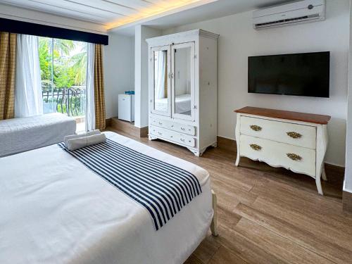 a bedroom with a bed and a dresser and a television at Hotel Boutique Recanto da Passagem in Cabo Frio