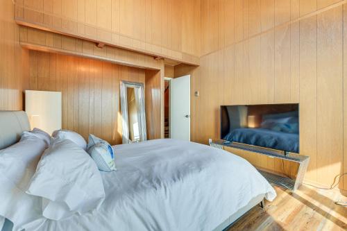 a bedroom with a large white bed and a television at Decks and Views Waterfront Shelton Home in Shelton