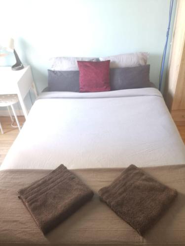 - un grand lit blanc avec 2 oreillers bruns dans l'établissement Studio Asnieres sur Seine équipé et fonctionnelle, à Asnières-sur-Seine