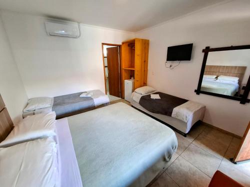 a hotel room with two beds and a mirror at Vila Palmar Hospedagem in Vassouras