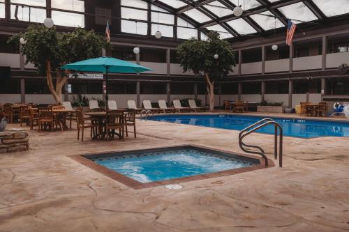 a swimming pool with tables and chairs and an umbrella at Americinn by Wyndham Appleton Downtown in Appleton
