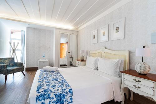 a bedroom with a large white bed and a chair at Hotel Boutique Recanto da Passagem in Cabo Frio