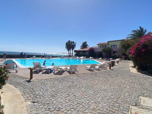 a swimming pool with chairs and the ocean in the background at Porto Antigo 1 - Three Bedroom, Pool & Wifi in Santa Maria