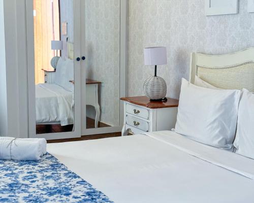 a bedroom with a white bed and a mirror at Hotel Boutique Recanto da Passagem in Cabo Frio