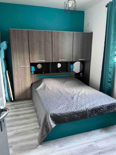 une chambre avec un grand lit avec un mur bleu dans l'établissement Le petit mauricia, à San-Nicolao