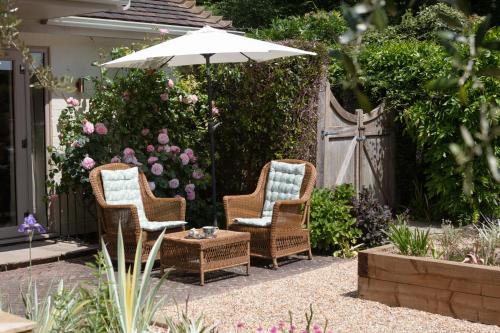 two chairs and an umbrella in a garden at Nest Stay By The Butler Collection in Pulborough