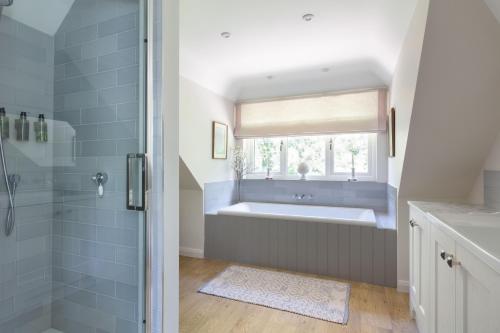 a bathroom with a bath tub and a window at Nest Stay By The Butler Collection in Pulborough